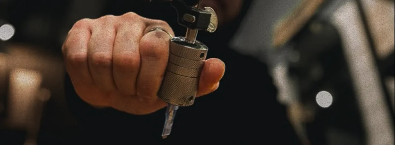 Close-up of a hand holding a tattoo machine grip with needle.