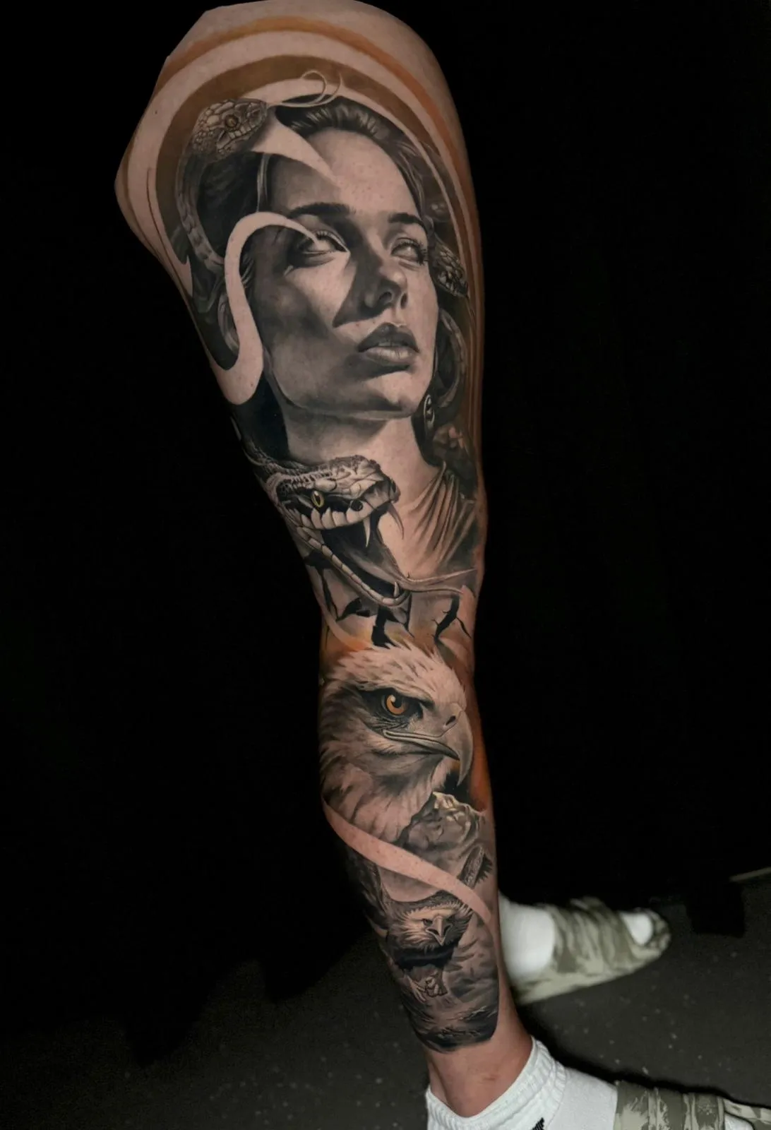 Black and gray tattoo sleeve featuring a woman's face with snakes intertwined, a fierce snake with open mouth, and a detailed eagle head.